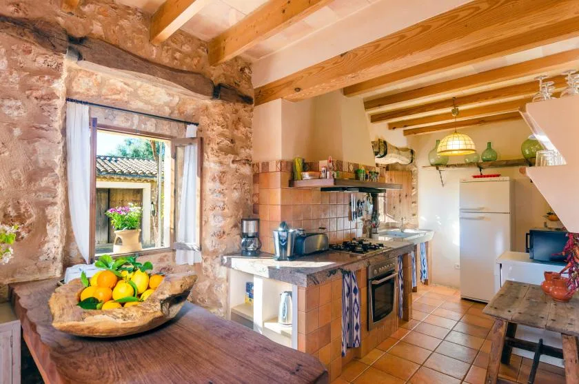 Una cocina rústica con paredes de piedra, vigas de madera y una encimera.