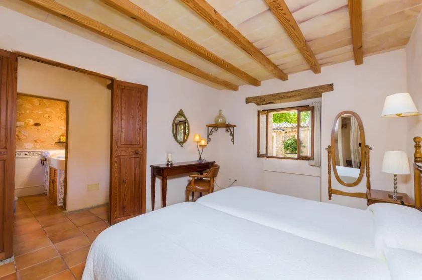 Un dormitorio con una cama, vigas de madera en el techo y una ventana.