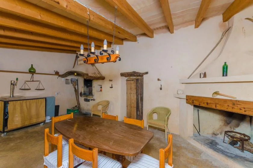 Un comedor rústico con una mesa de madera, sillas y vigas expuestas en el techo.