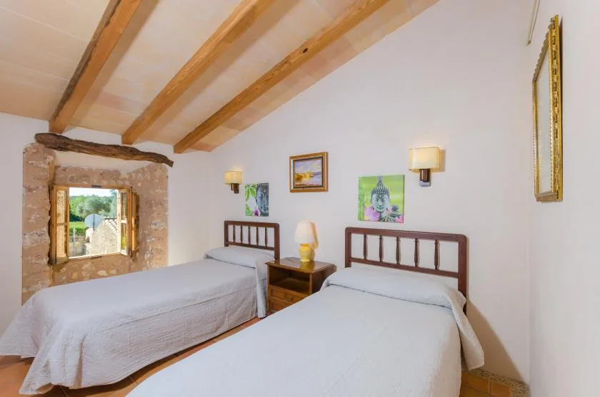Un dormitorio con dos camas bajo vigas de madera vistas en el techo.