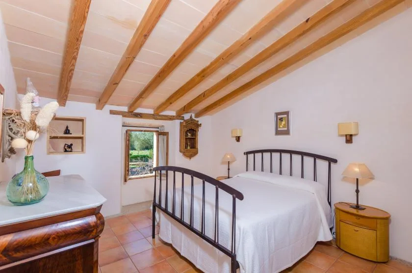 Un dormitorio con una cama doble, vigas de madera vistas y mesitas de noche.