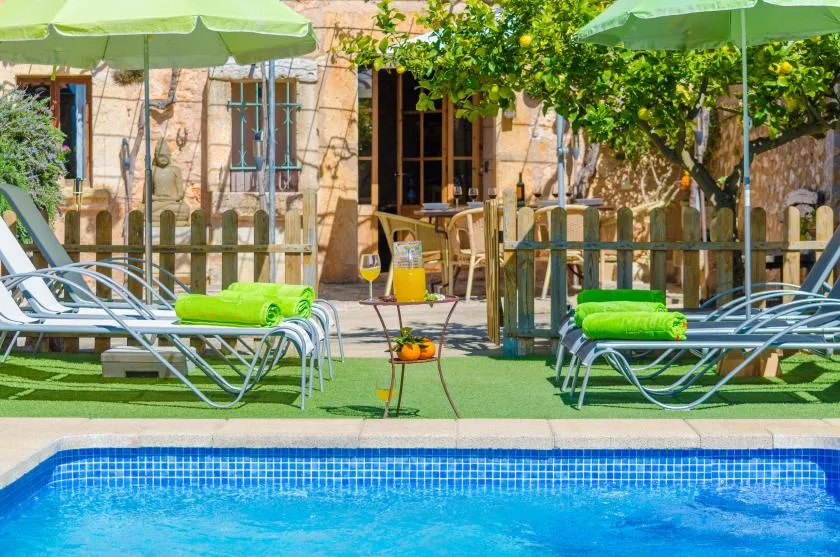 Una piscina rodeada de tumbonas y sombrillas verdes.