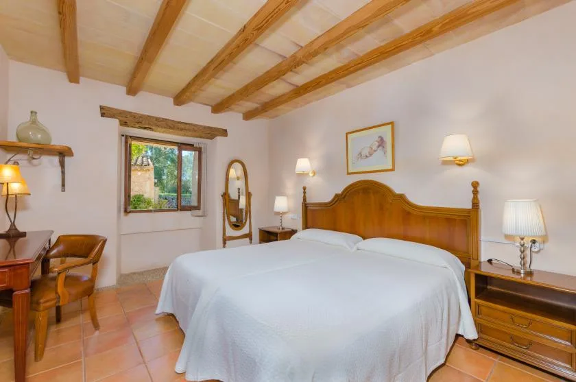 Un dormitorio con una cama grande, cabecero de madera y vigas vistas en el techo.