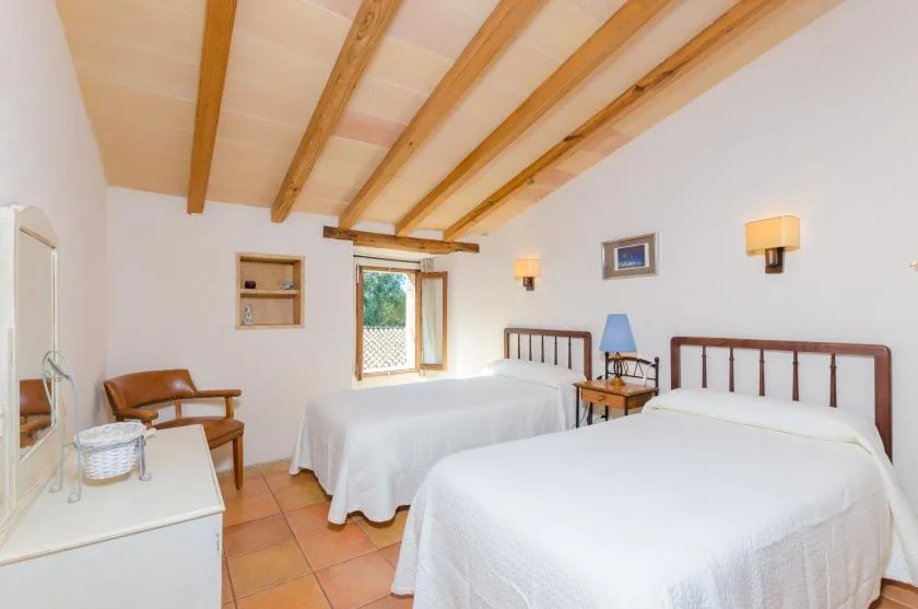 Un dormitorio con dos camas, vigas expuestas en el techo y una ventana.