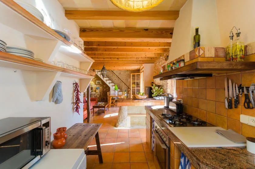 Una cocina rústica con vigas de madera en el techo y una larga encimera alicatada.