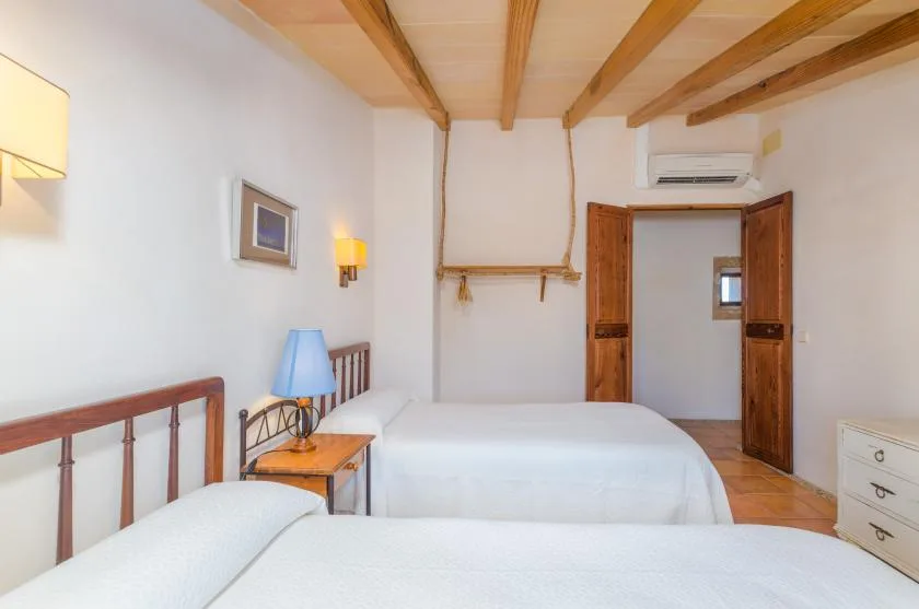 Un dormitorio con dos camas, vigas de madera en el techo y una puerta abierta.