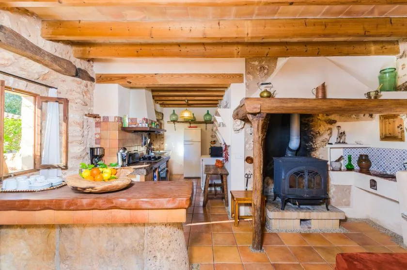 Una cocina y comedor rústicos con una barra central y una estufa de leña.