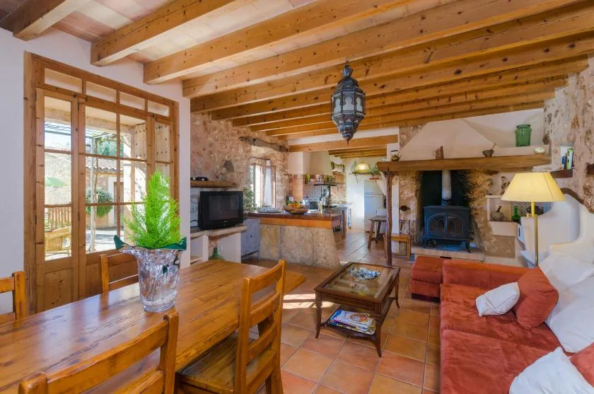 Una sala de estar y comedor rústica con vigas de madera, una mesa y una chimenea.