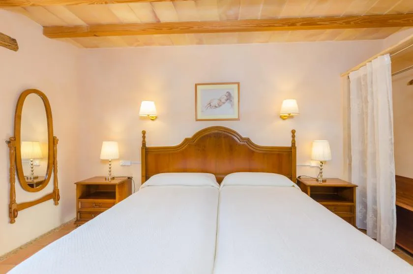Un dormitorio con una cama de madera, mesitas de noche y un espejo en la pared.
