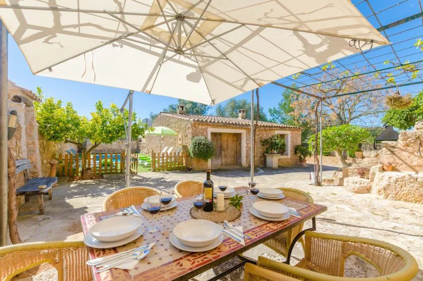 Una zona de comedor al aire libre con una mesa puesta bajo una gran sombrilla.