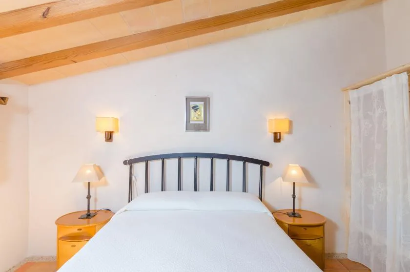 Un dormitorio con una cama bajo vigas de madera expuestas en el techo.