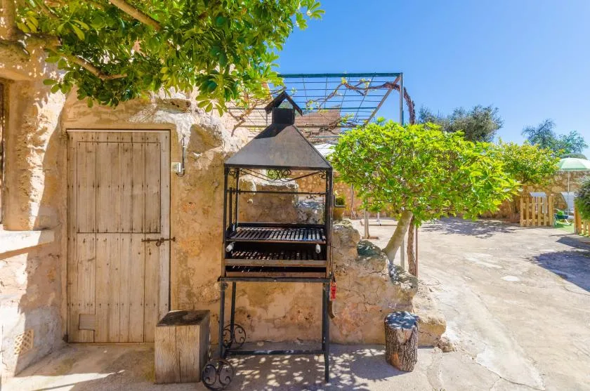 Una zona de cocina al aire libre con una parrilla junto a un edificio de piedra rústica.