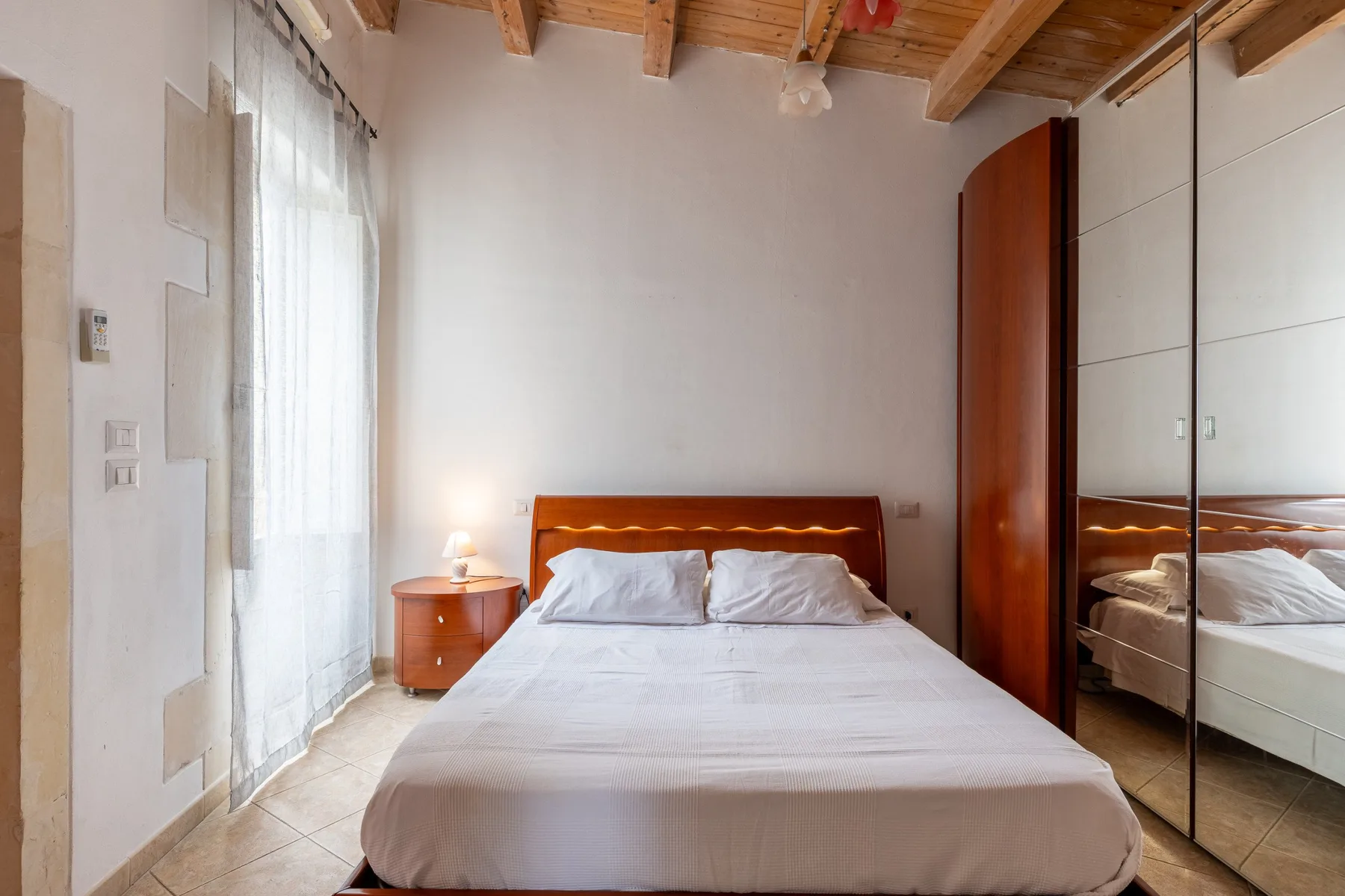 Un dormitorio con una cama, una mesita de noche y un armario con espejo.