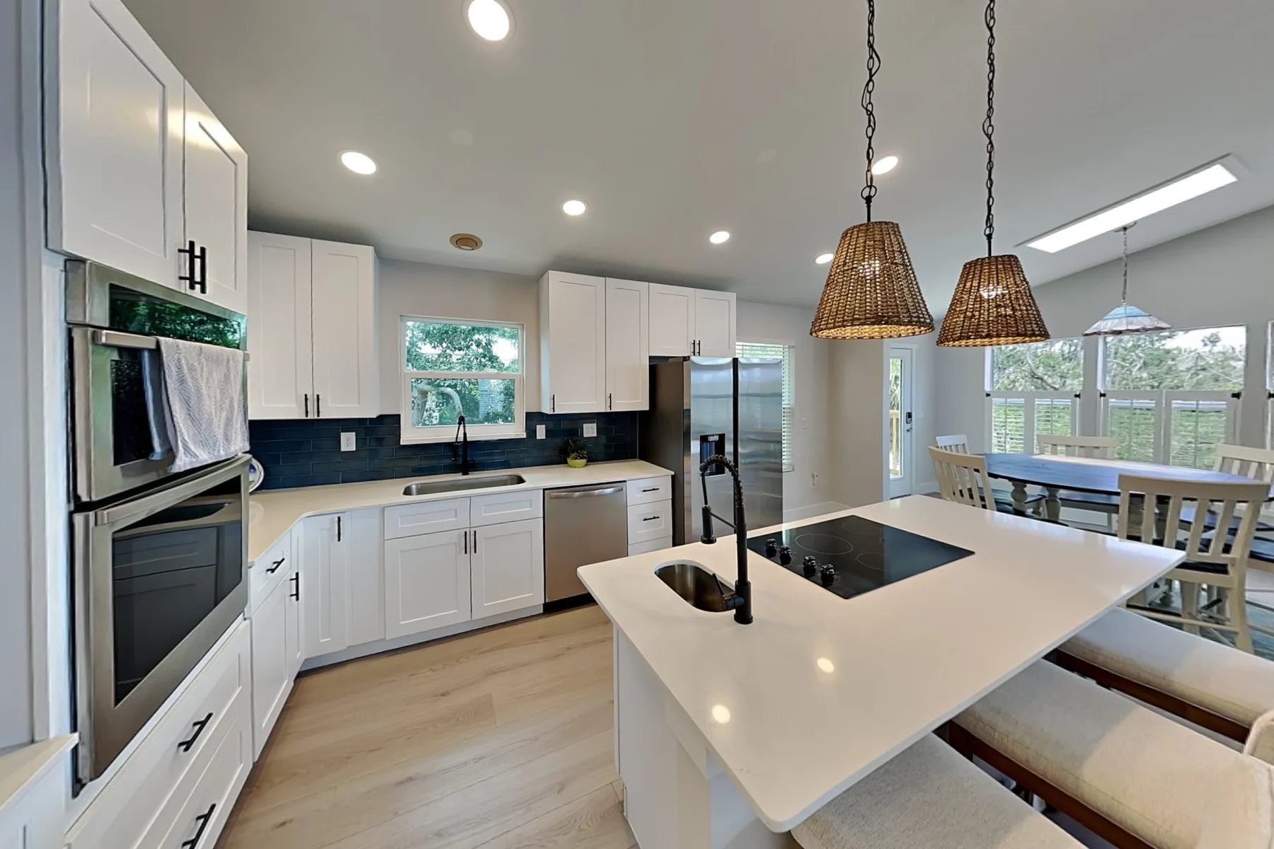 A bright kitchen with a large island and dining area beside the windows.