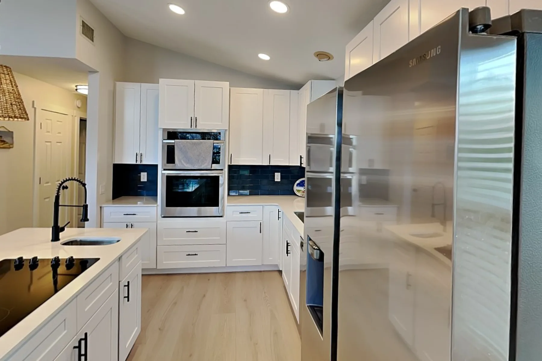 A bright kitchen with white cabinets, dark countertops, and stainless steel appliances.
