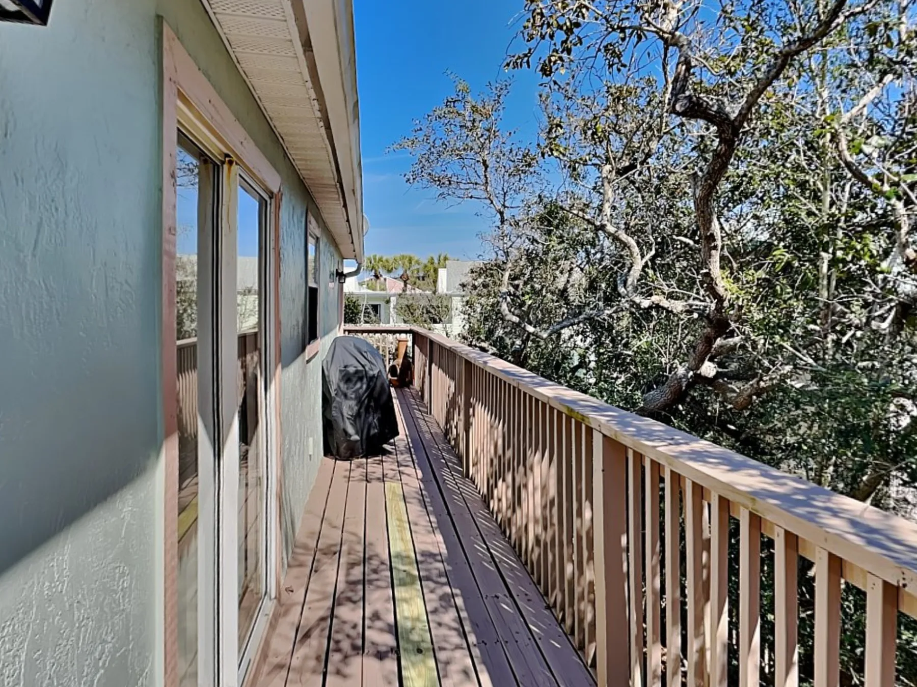 A narrow outdoor deck runs alongside the building, bordered by a wooden railing.