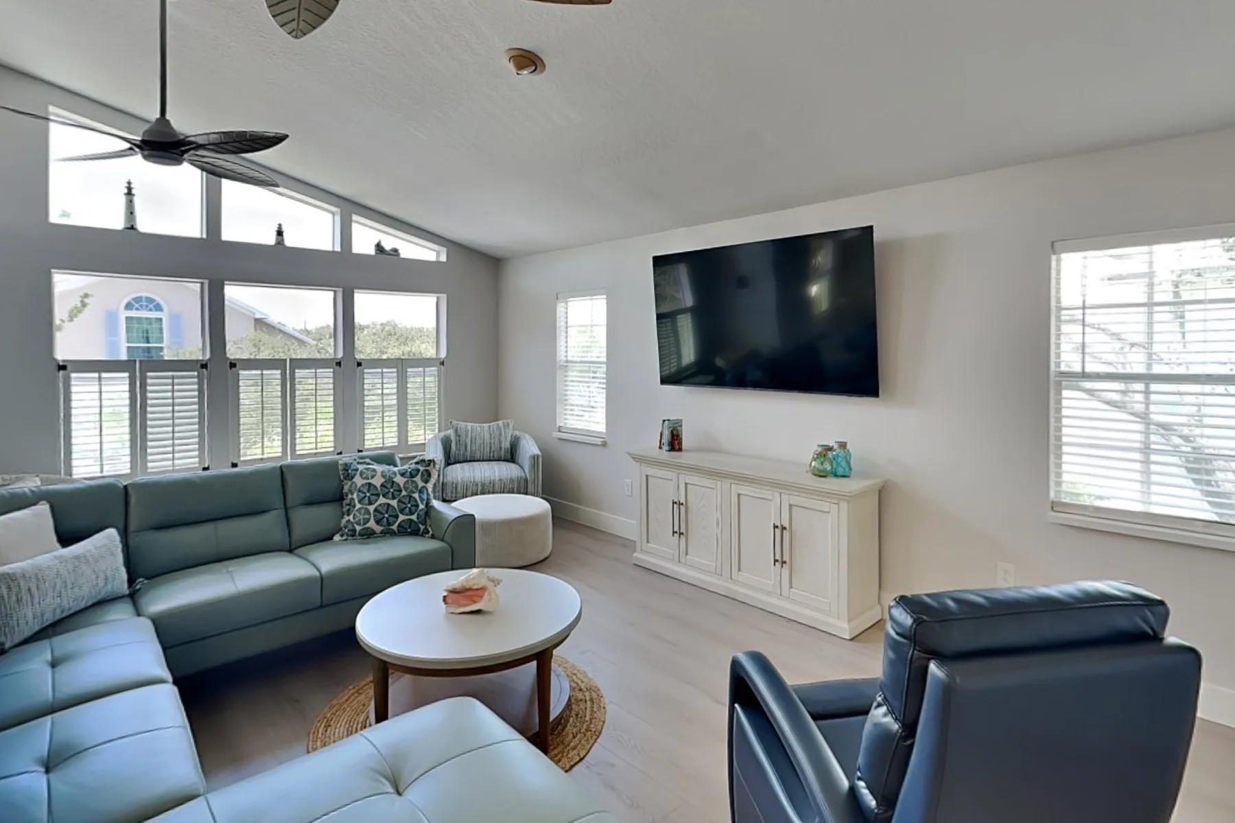 Living room with seating arranged around a coffee table and wall-mounted television.