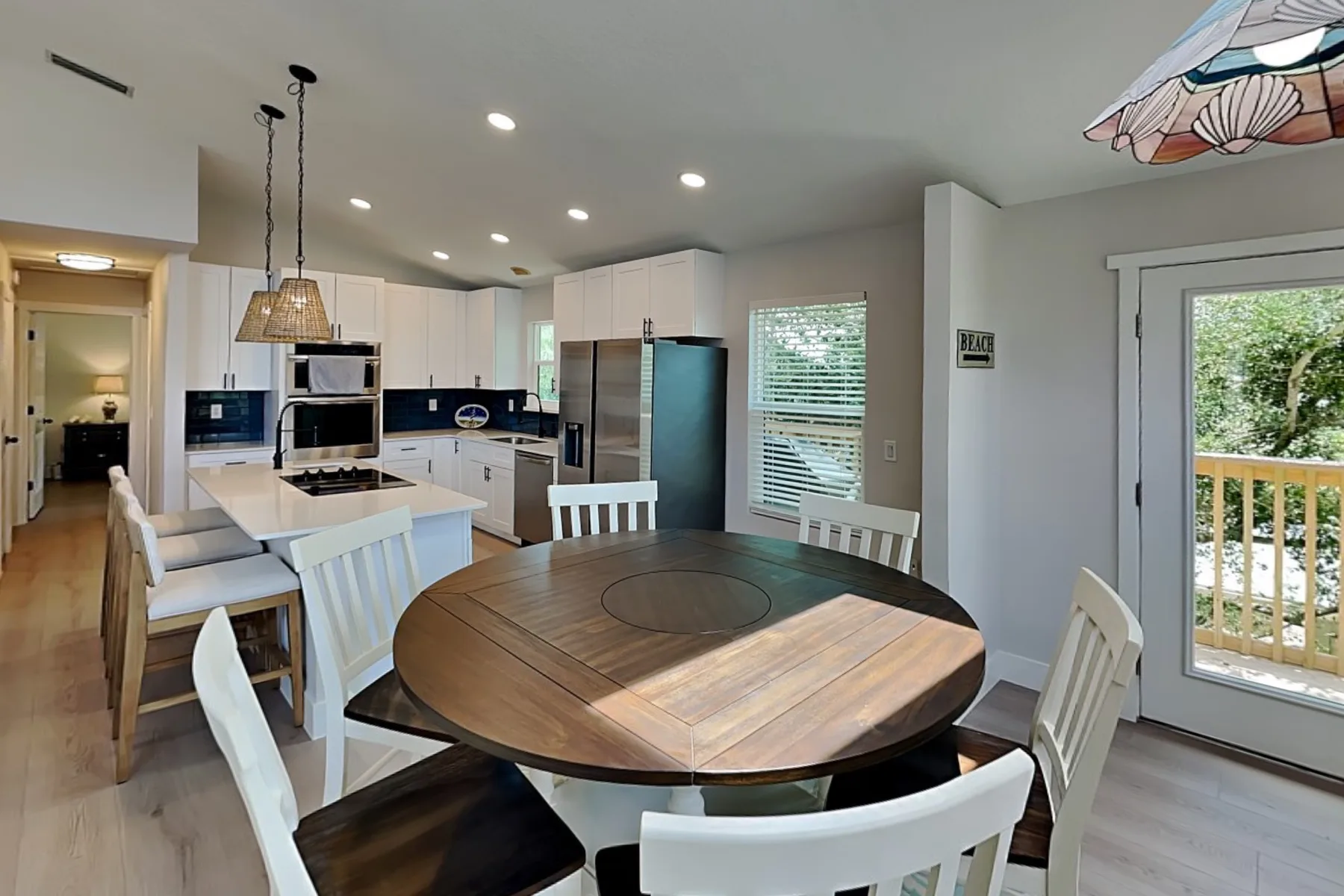 An open kitchen and dining area with a round wooden table and white seating.
