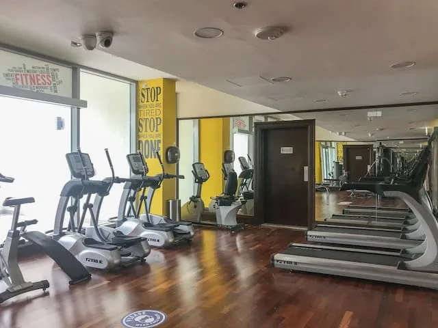 A fitness room with cardio machines arranged along mirrored walls.