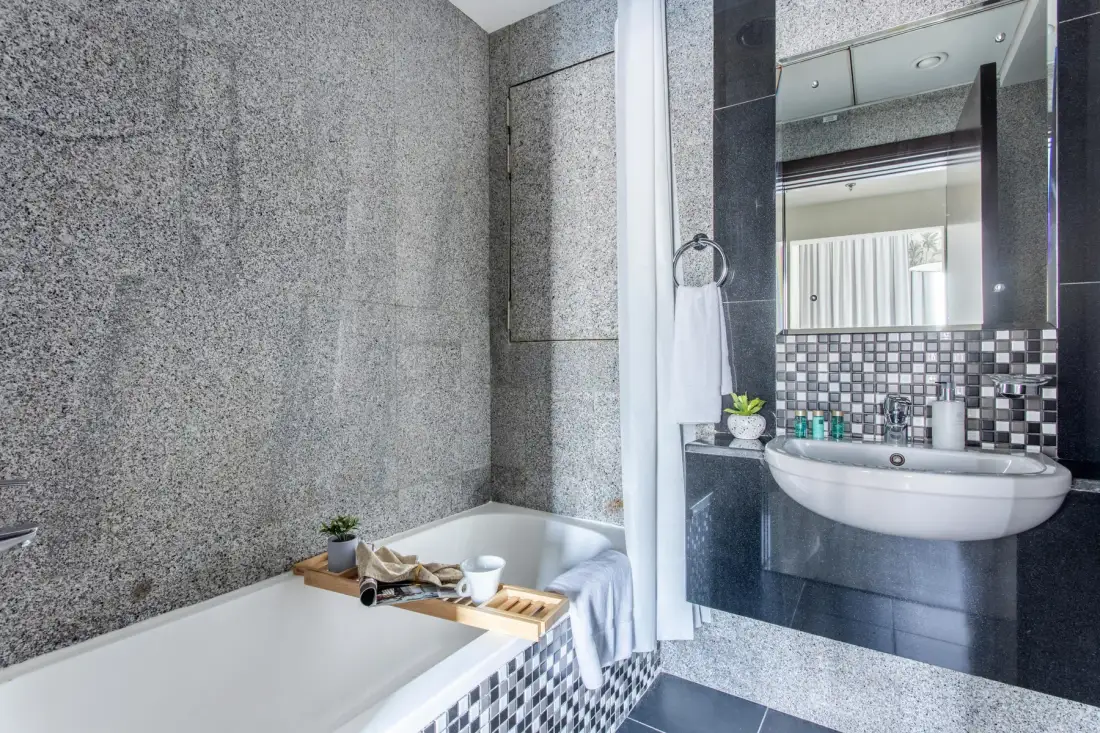 A bathroom with a bathtub and a sink beside a large mirror.