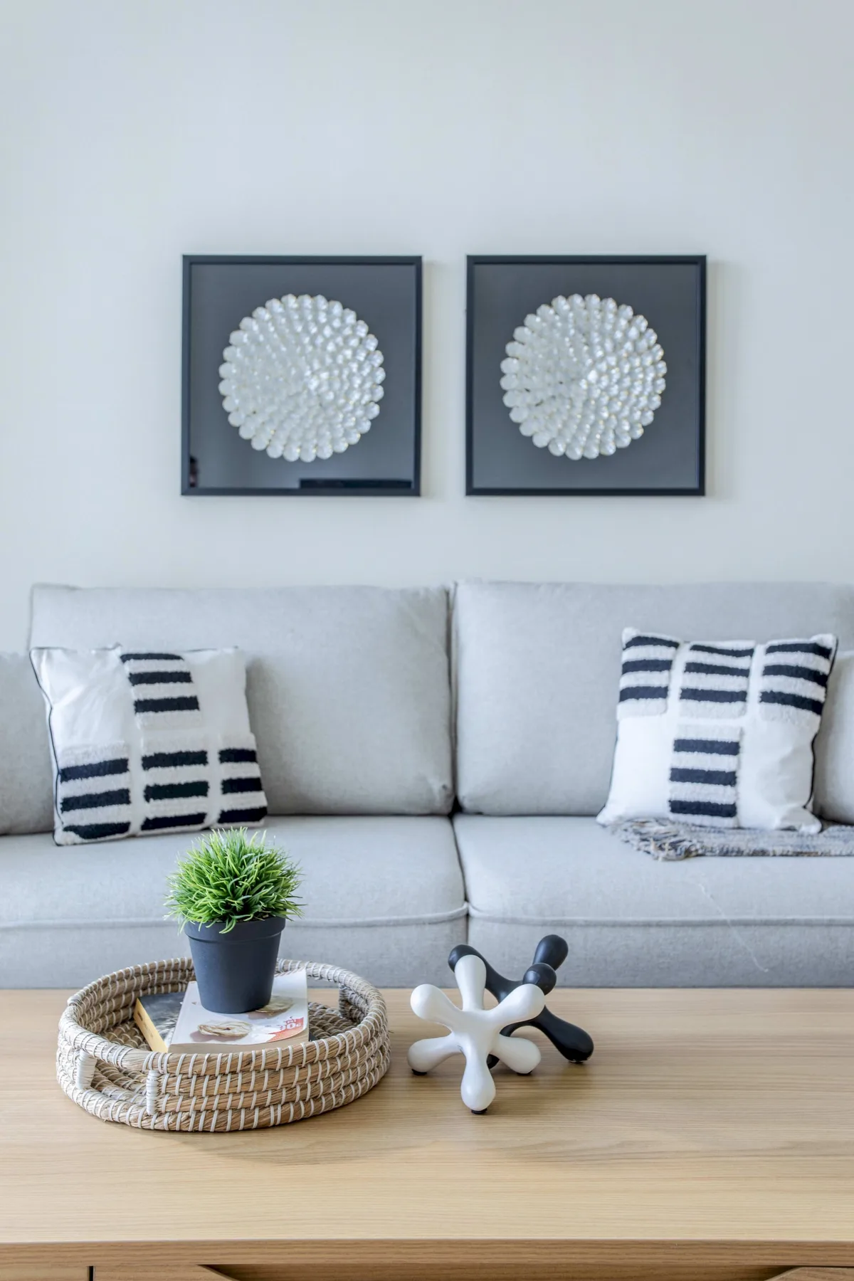 A living room with a light sofa, framed wall art, and a wooden coffee table.