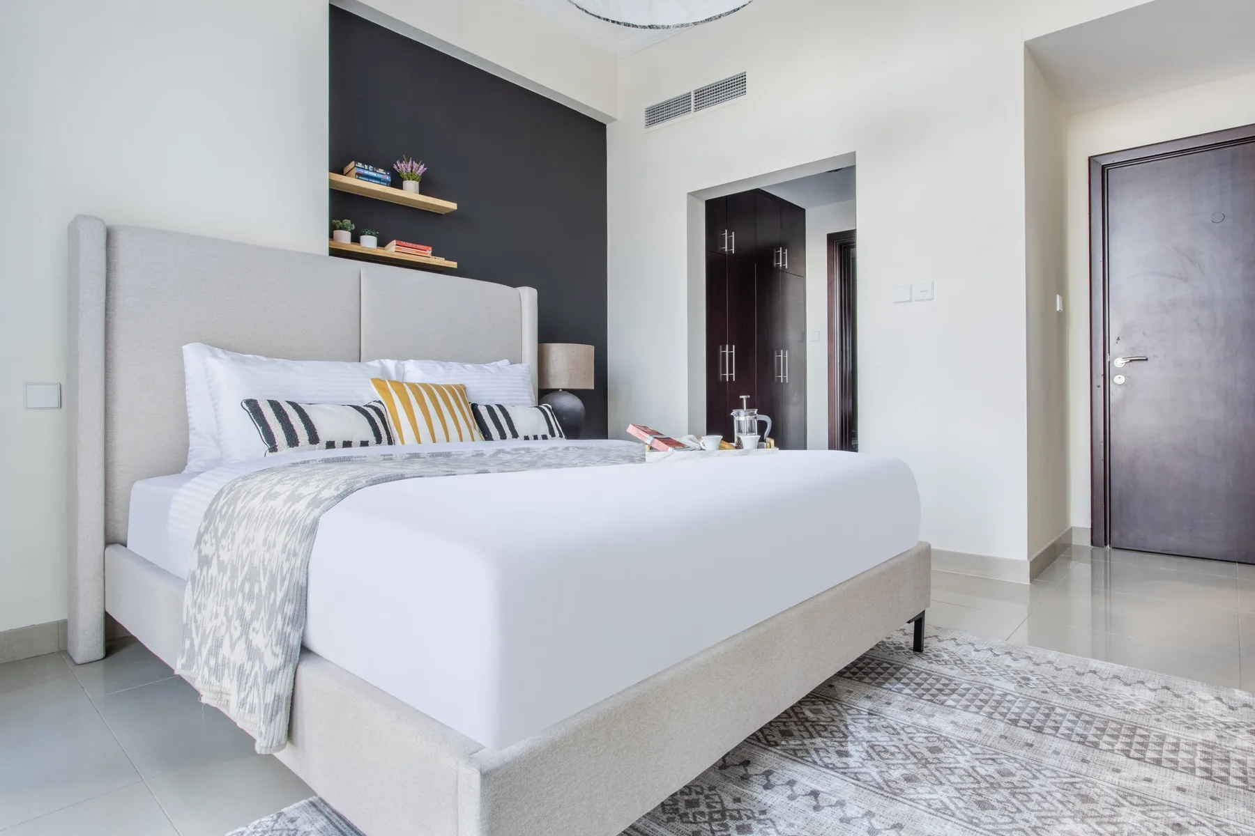 A bright bedroom with a large bed and patterned rug.