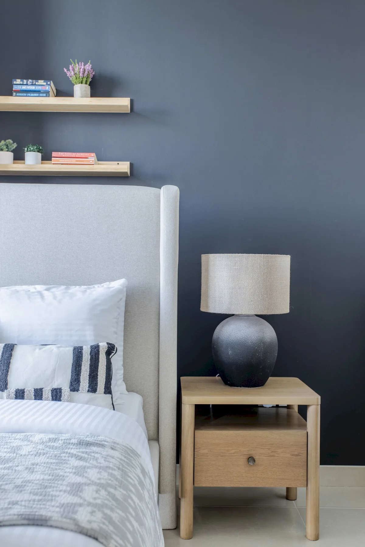A bedroom with a neatly made bed and a wooden bedside table.