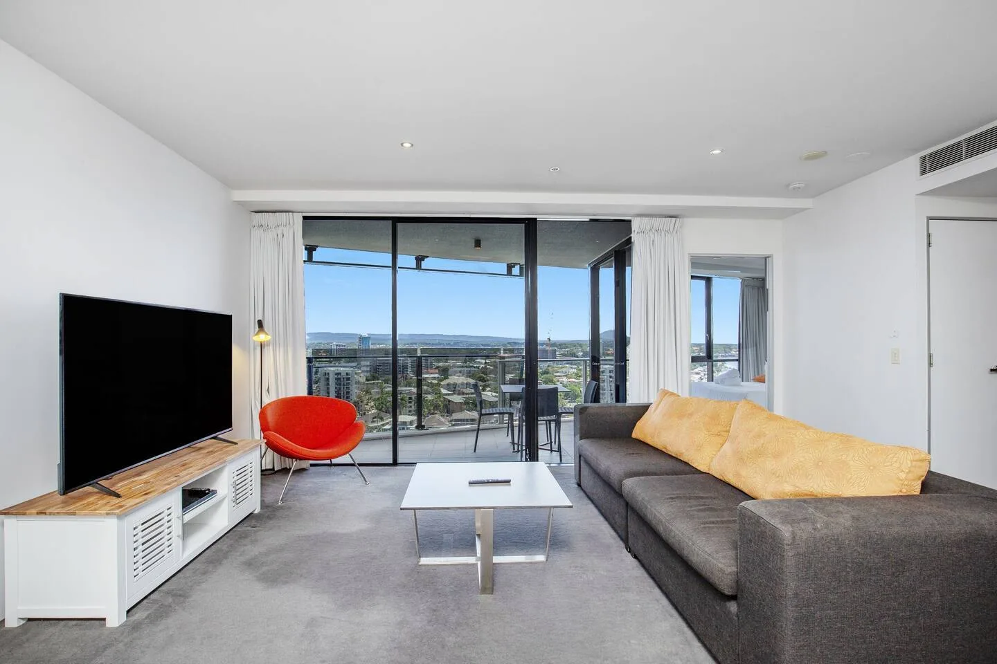 A living room with seating, a television, and large windows overlooking the city.