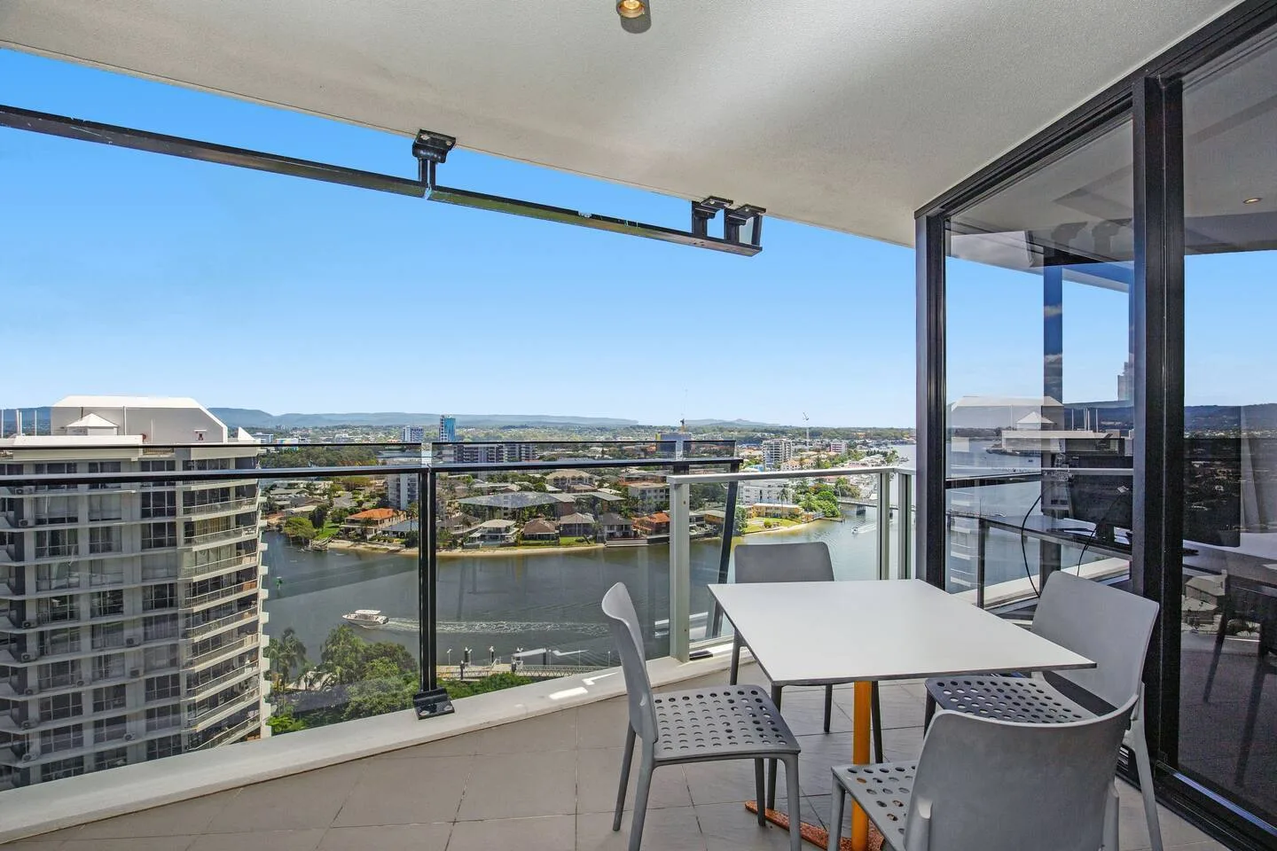 A balcony seating area overlooks a river and nearby buildings.