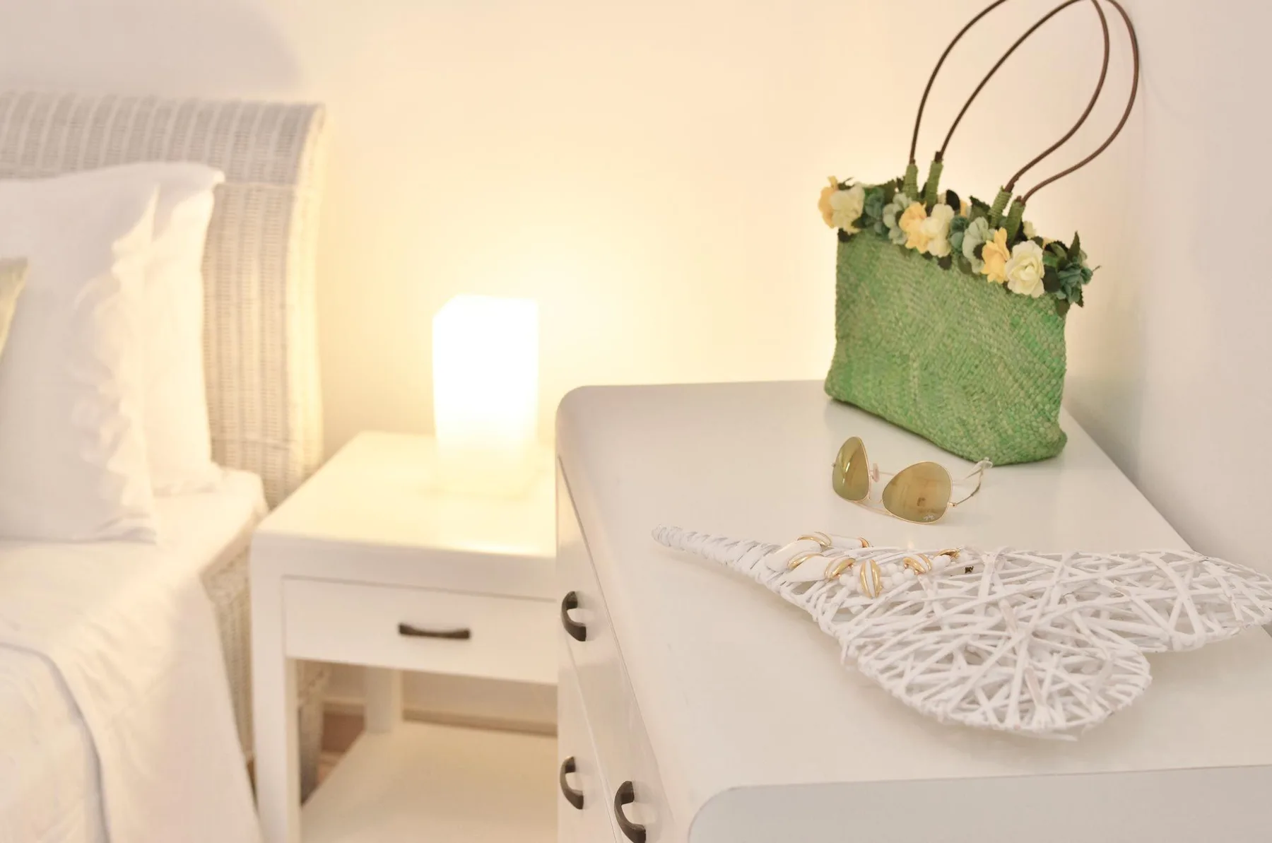 A bedroom bedside table holds a green bag and decorative items.