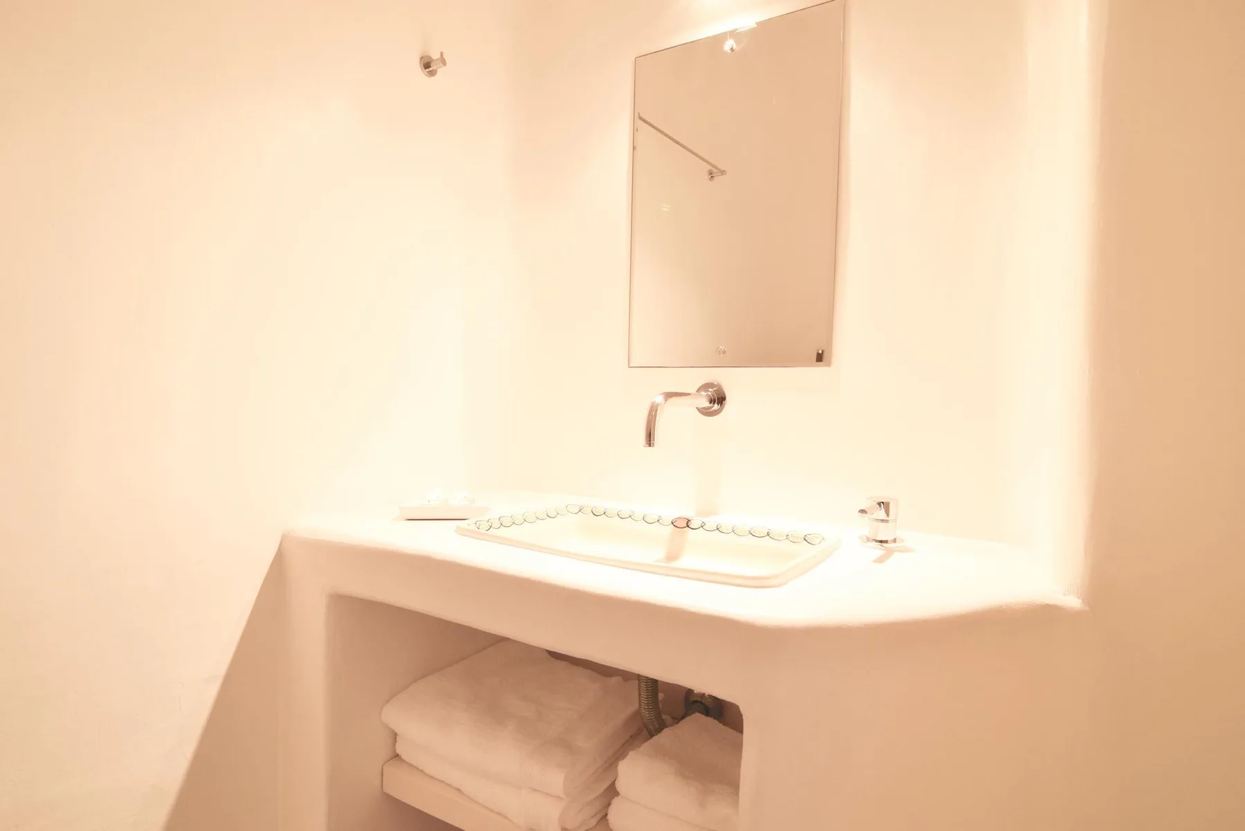 A bathroom vanity with a sink, mirror, and folded towels below.