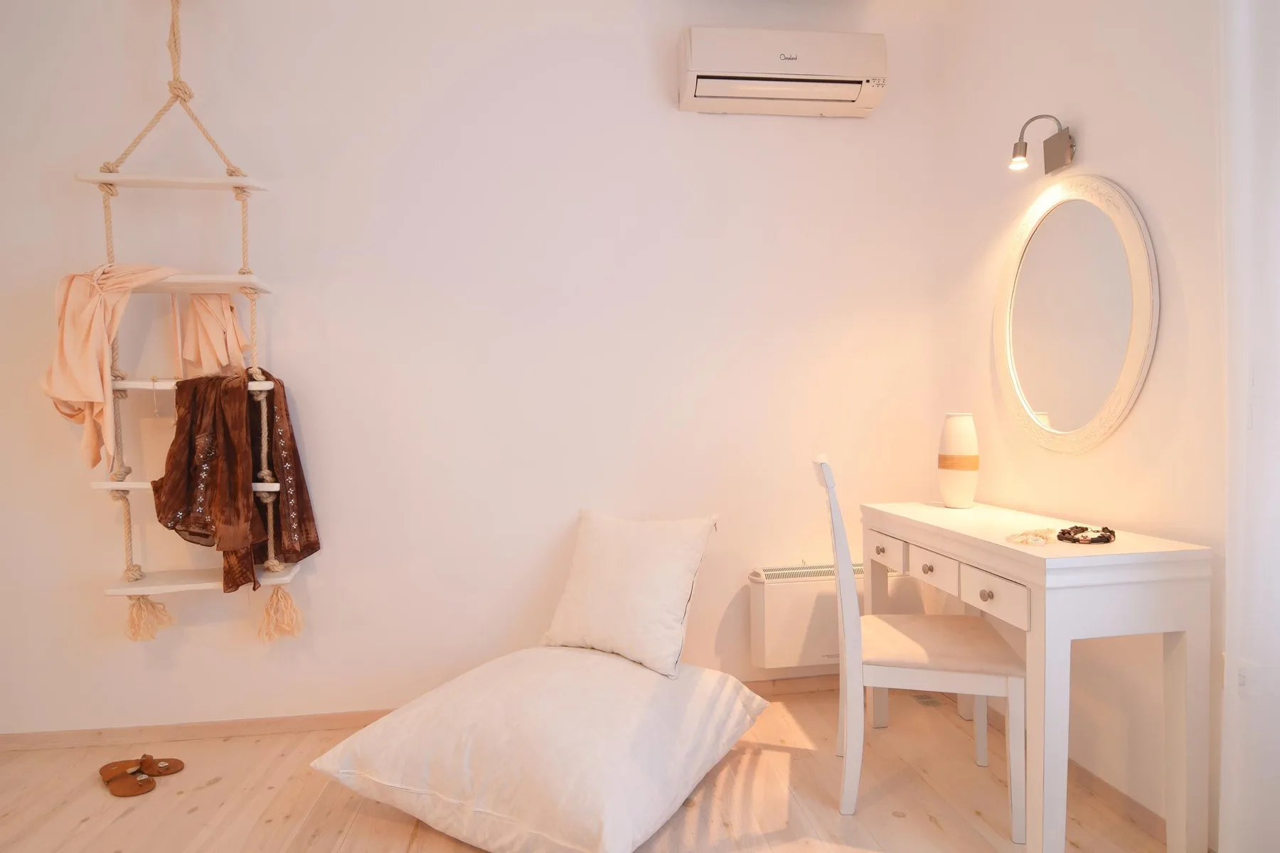A softly lit bedroom corner with a floor cushion and white dressing table.