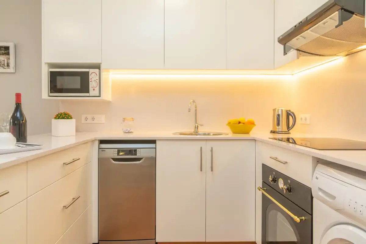 Una cocina moderna y luminosa con armarios blancos y electrodomésticos de acero inoxidable.