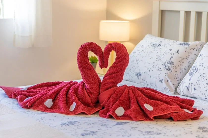 Un dormitorio con toallas rojas acomodadas en forma de cisnes sobre la cama.