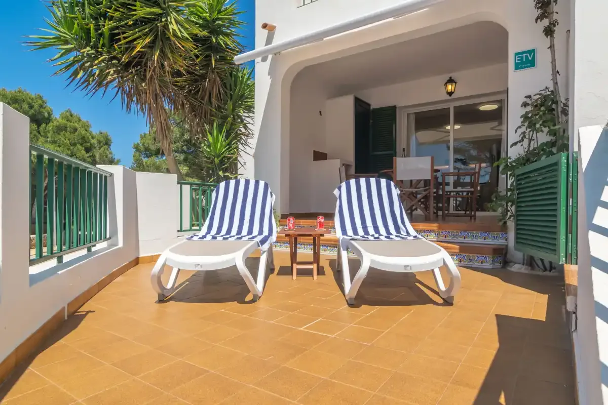 Un patio soleado con dos tumbonas da a una puerta abierta hacia el comedor.