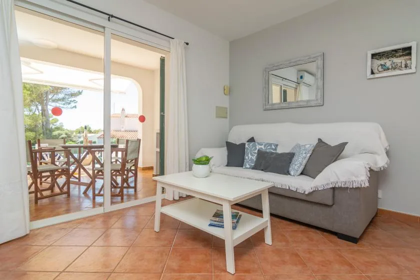 Una sala de estar con sofá y mesa de centro junto a una puerta de vidrio que da a un patio.