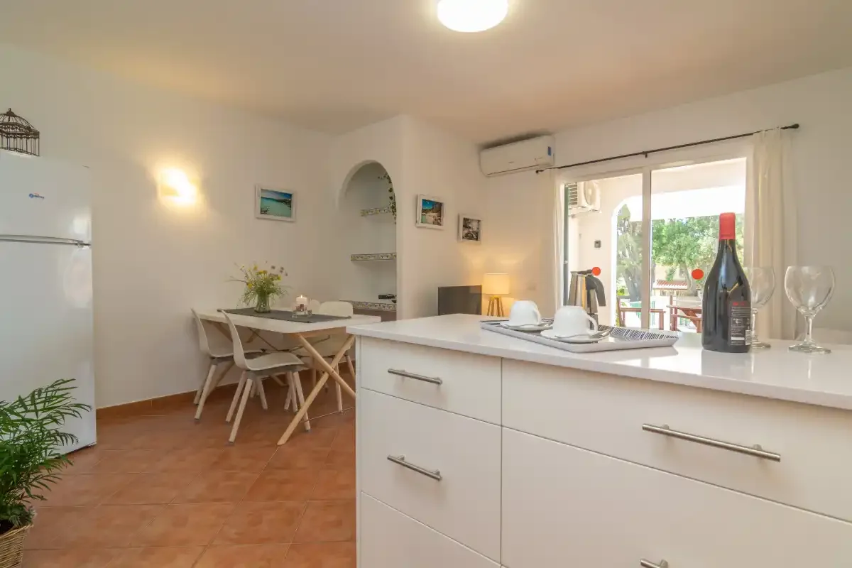 Una cocina luminosa con zona de comedor y una barra junto a una puerta de cristal.