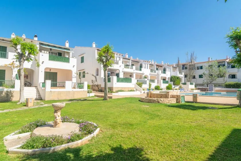 Un patio ajardinado con edificios de apartamentos, césped verde y una piscina.