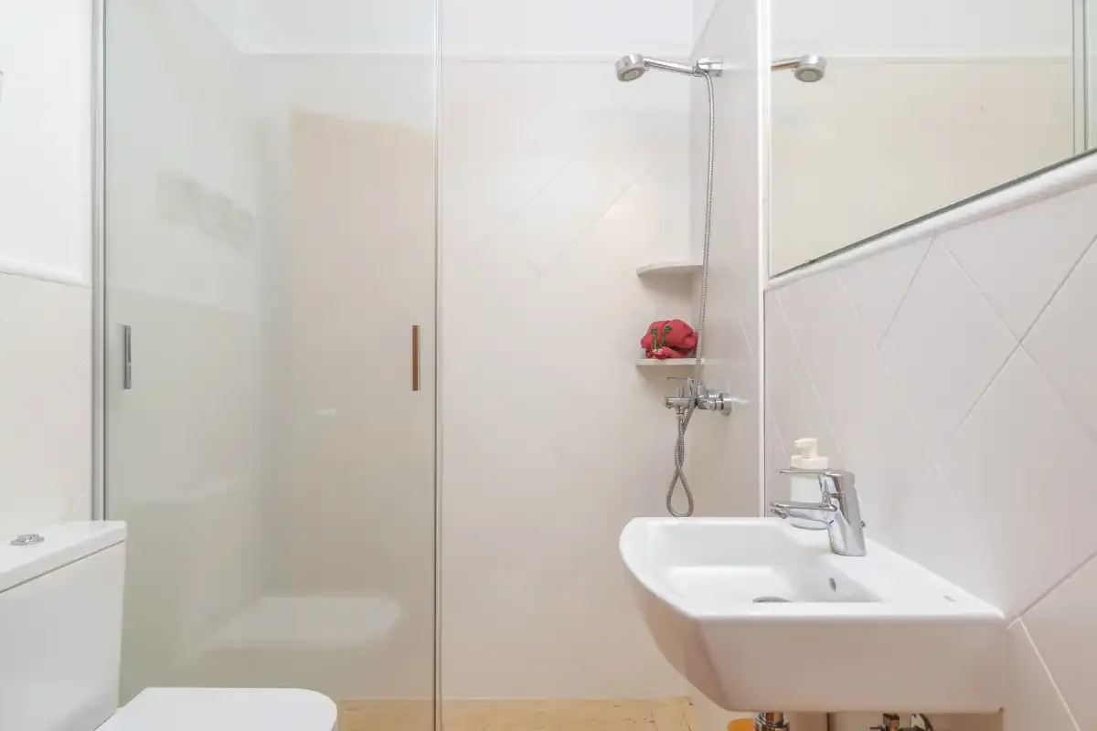 Un baño luminoso con ducha de cristal y lavabo de pared.