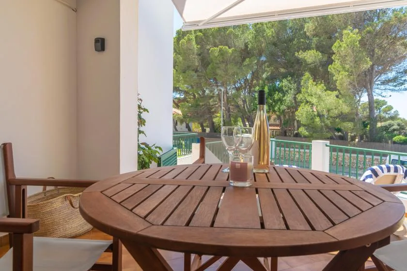 Una mesa redonda está en una terraza cubierta con vistas a árboles frondosos.