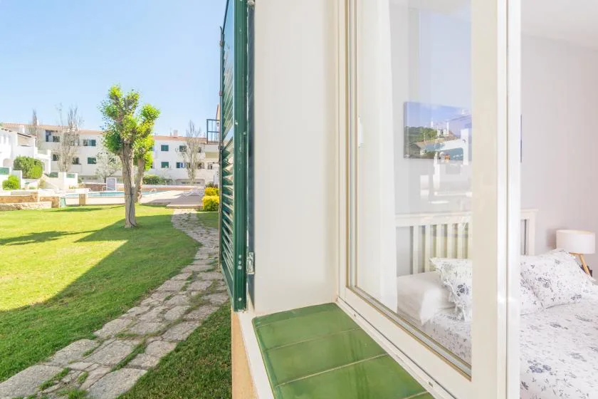 Un dormitorio da a un patio verde a través de una ventana amplia.