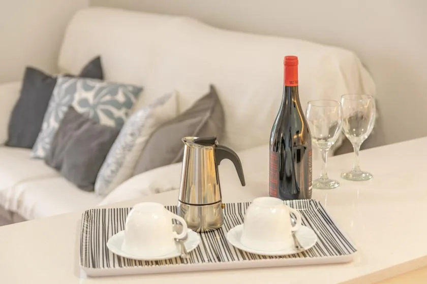Una zona de estar con una bandeja de café y copas de vino sobre una mesa.