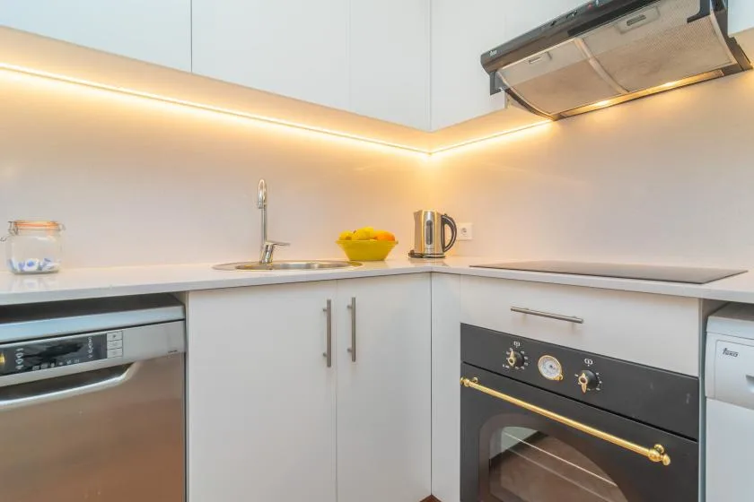 Una cocina moderna con gabinetes blancos, encimera y electrodomésticos integrados.