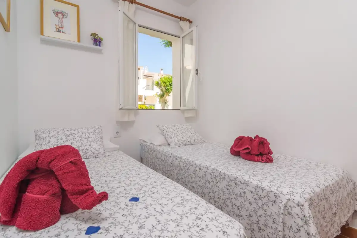 Un dormitorio con dos camas y una ventana abierta.