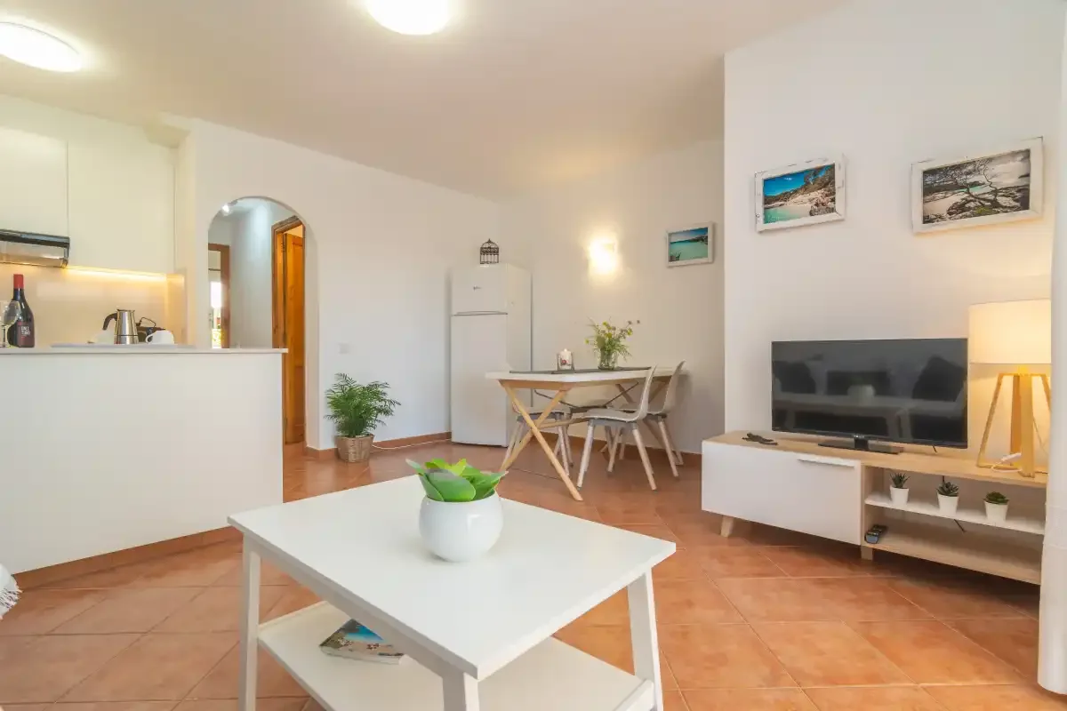 Una luminosa sala de estar y comedor diáfana con televisor y mesa de comedor.