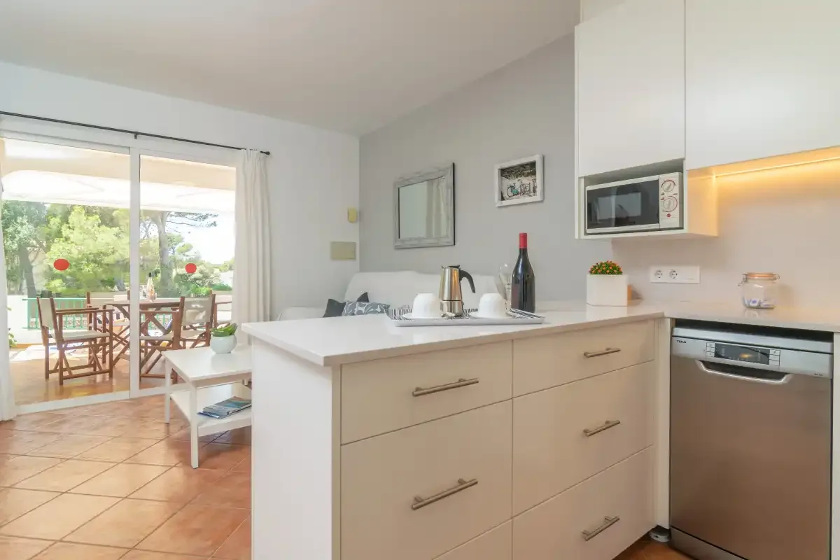 Una cocina luminosa con una isla central y puertas corredizas que dan a un patio amueblado.