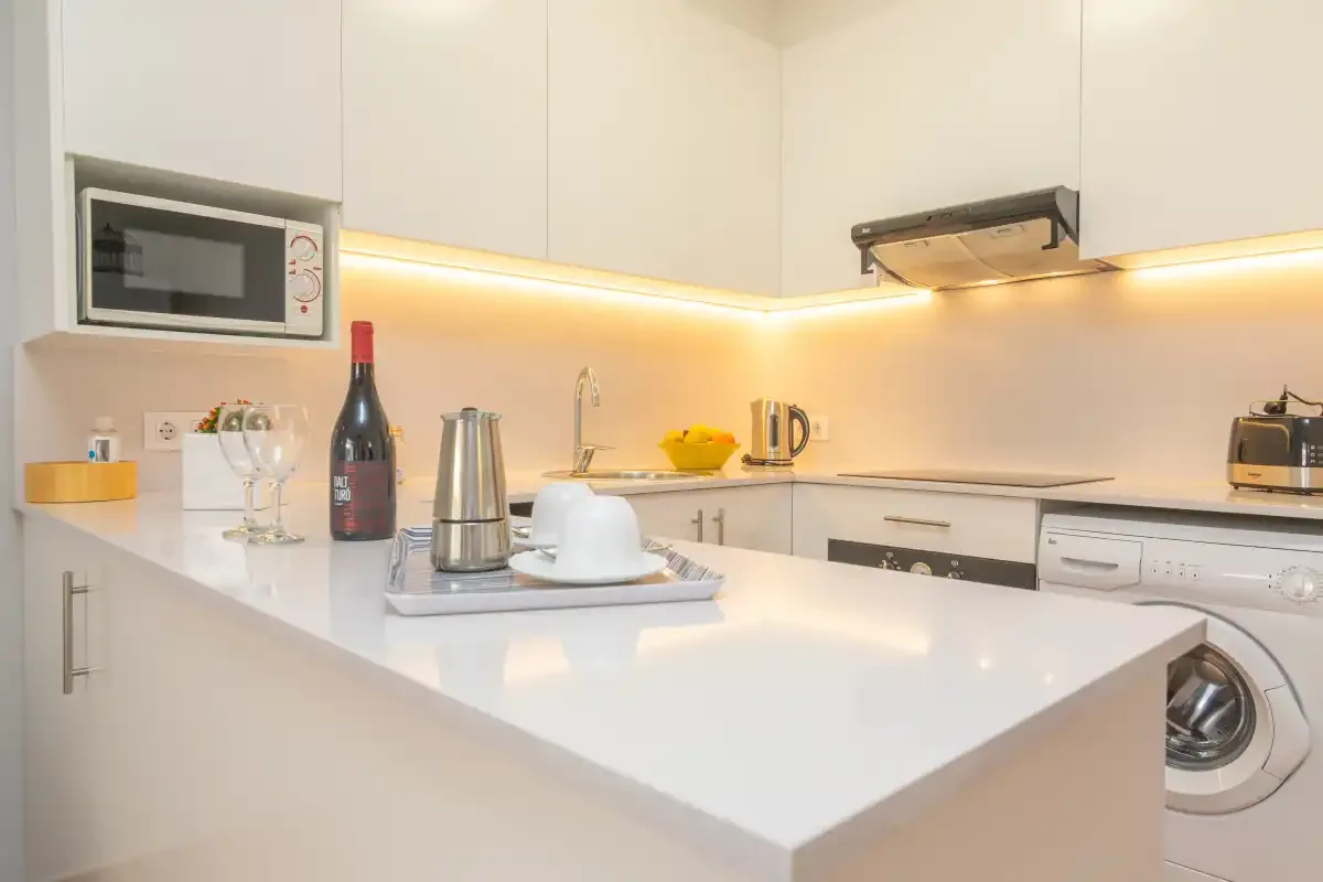 Una cocina luminosa y moderna con una gran isla blanca y electrodomésticos integrados.