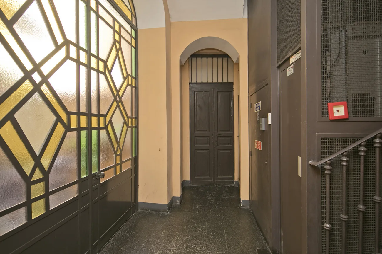 Un recibidor interior con una puerta oscura bajo un arco.