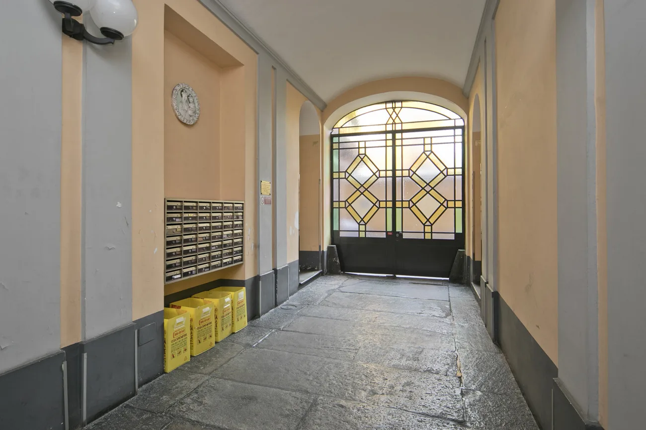 Un pasillo de entrada interior con una puerta de vidrio decorativo al fondo.