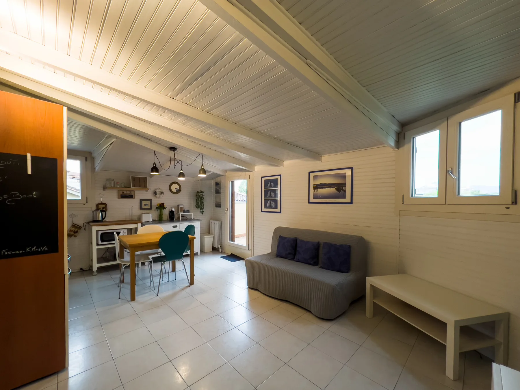 Una luminosa sala-comedor diáfana con mesa, asientos y cocina.